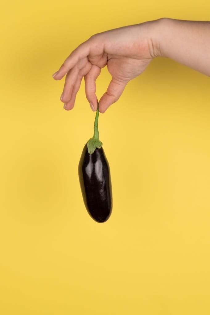 Hand holding tray of eggplant seeds under grow light