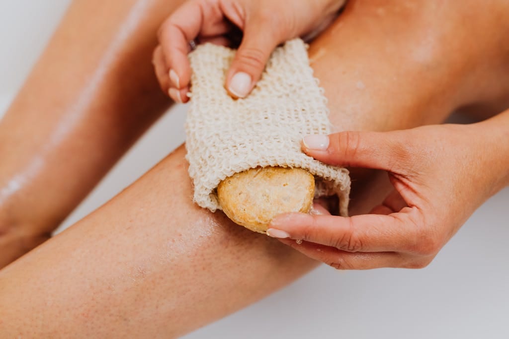 Hands tending loofah vine, small loofahs forming.