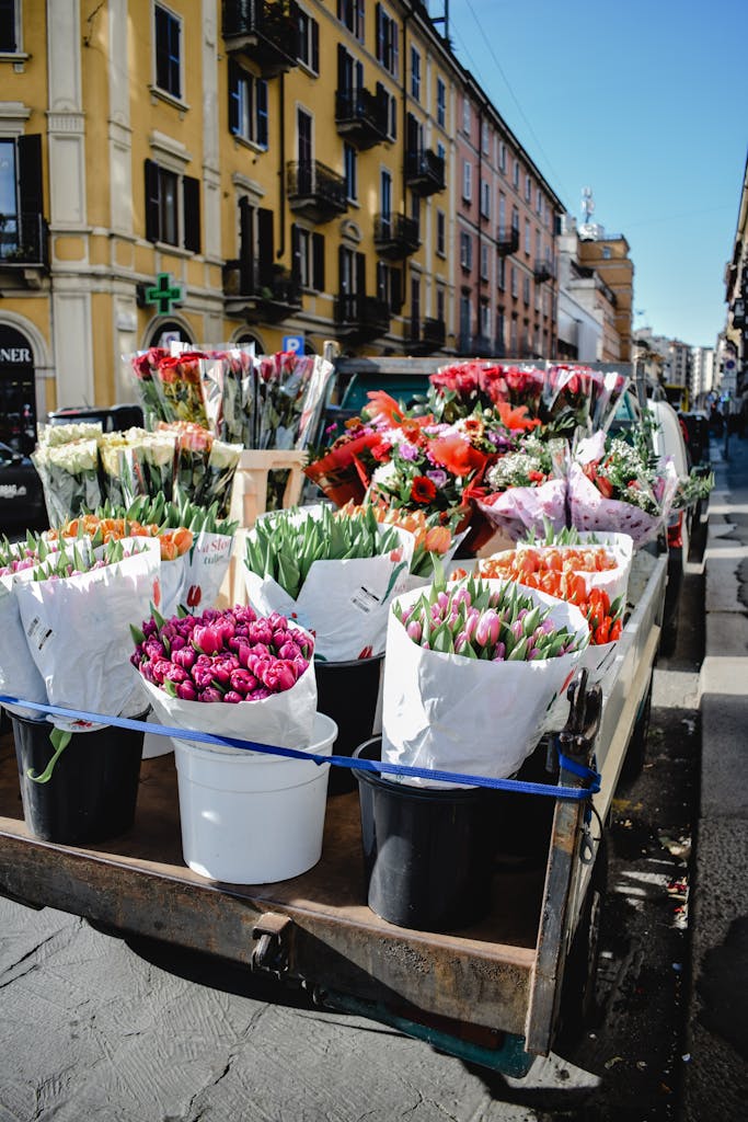 Variety of vertical planters with vegetables on a balcony, city backdrop.