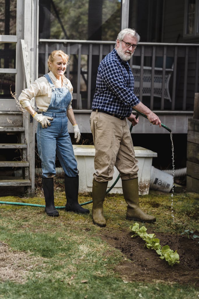 Senior couple watering plants in garden